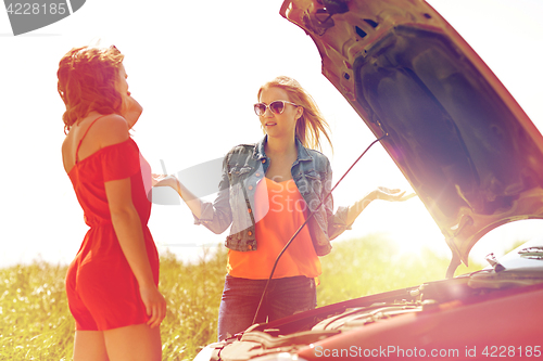 Image of women with open hood of broken car at countryside