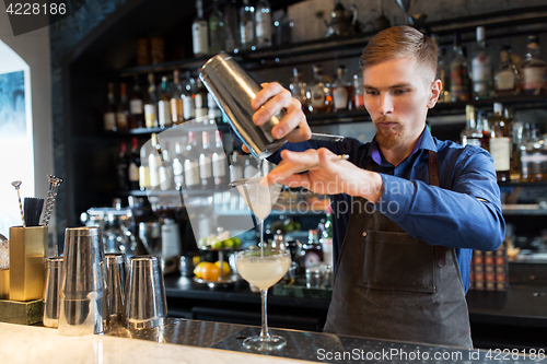 Image of barman with shaker preparing cocktail at bar