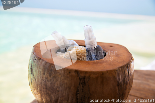 Image of body lotion spray in coconut shell at beach spa