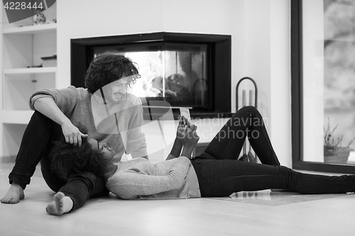 Image of multiethnic couple used tablet computer on the floor