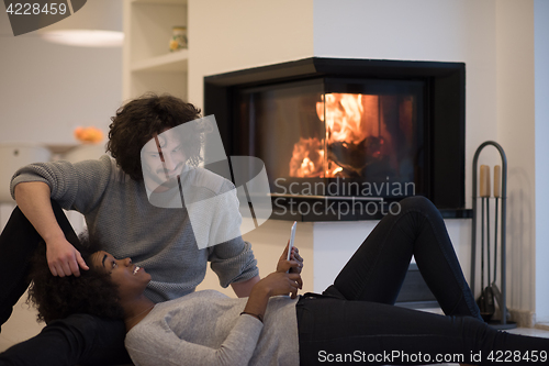 Image of multiethnic couple using tablet computer on the floor