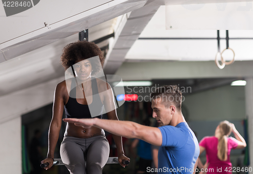 Image of black woman doing parallel bars Exercise with trainer