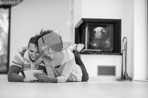 Image of multiethnic couple used tablet computer on the floor