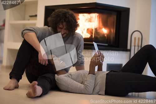 Image of multiethnic couple using tablet computer on the floor