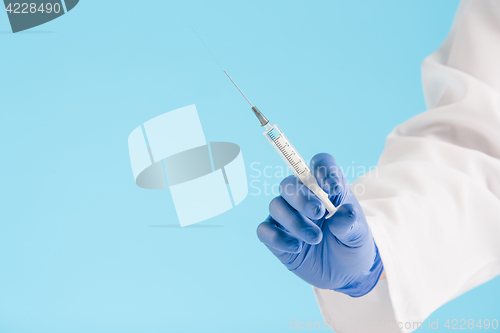 Image of Hand in a blue glove holding syringe on blue