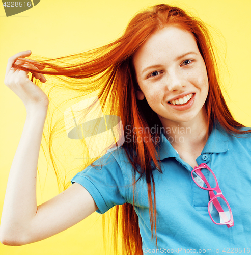 Image of Beauty and skin care. Highly-detailed portrait of attractive redhead teenage girl with charming smile and cute freckles having rest indoors wearing her hair loose. Beautiful woman relaxing at home on 