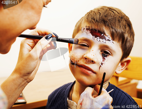 Image of little cute child making facepaint on birthday party, zombie Apocalypse facepainting, halloween preparing concept at home