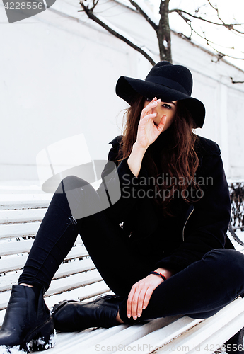 Image of young pretty modern hipster girl waiting on bench at winter snow park alone, lifestyle people concept 
