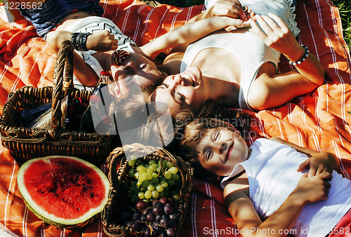 Image of cute happy family on picnic laying on green grass mother and kids, warm summer vacations close up, brother and sister, lifestyle people concept