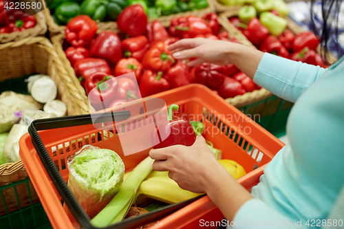 Image of woman with basket buying peppers at grocery store