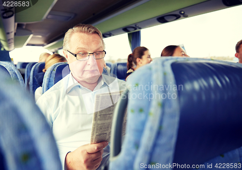 Image of happy senior man reading newspaper in travel bus