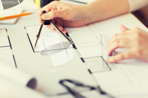 Image of close up of hands with compass measuring blueprint