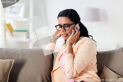 Image of happy indian woman calling on smartphone at home
