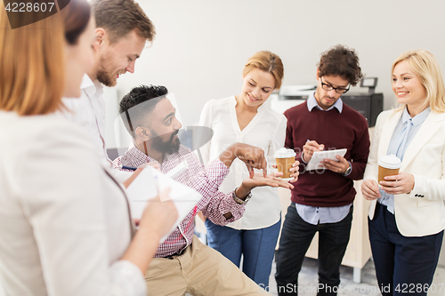 Image of happy business team with coffee talking at office