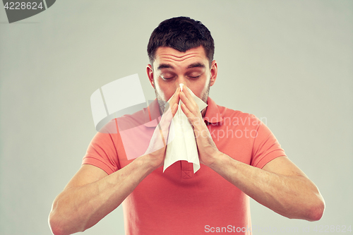 Image of sick man with paper napkin blowing nose