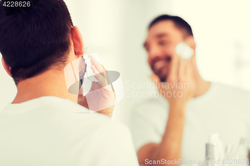 Image of close up of man applying shaving foam to face