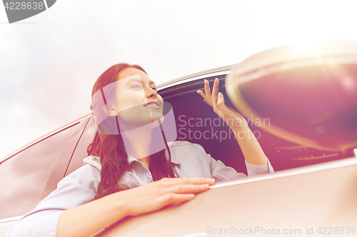 Image of happy young woman driving in car