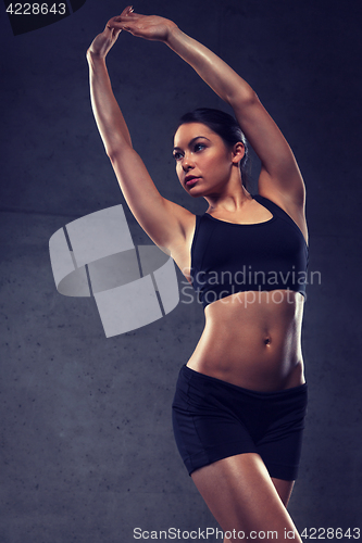 Image of young woman posing and showing muscles in gym