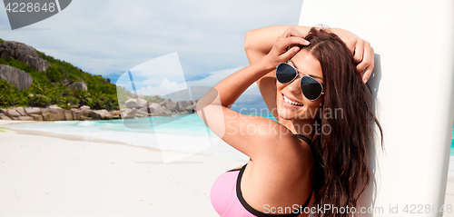 Image of smiling young woman with surfboard on summer beach