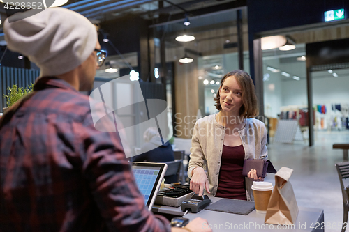 Image of happy woman paying for purchases at cafe