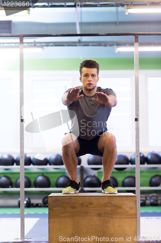 Image of young man doing box jumps exercise in gym