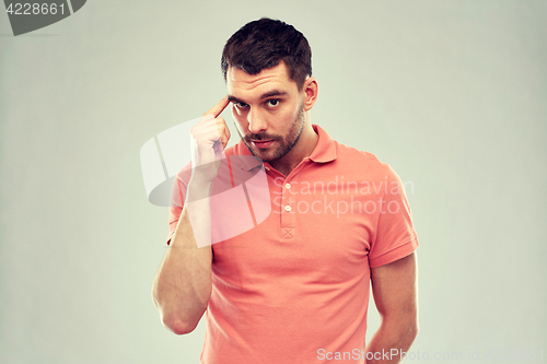 Image of man with finger at temple over gray background