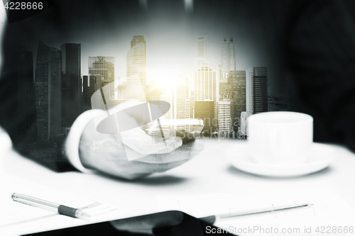 Image of businessman with smartphone and coffee at office