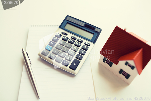 Image of close up of home model, calculator and notebook