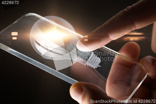 Image of hands with smartphone and lightbulb projection