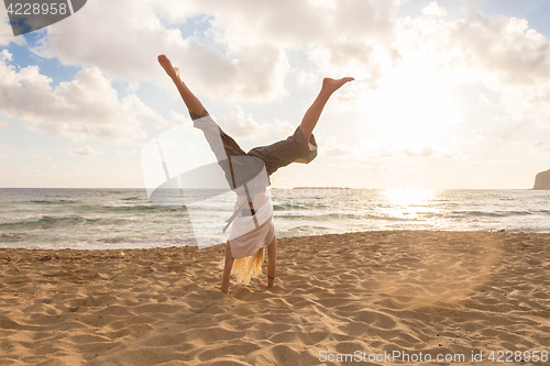 Image of Free Happy Woman Turning Cartwheel Enjoying Sunset on Sandy Beach.