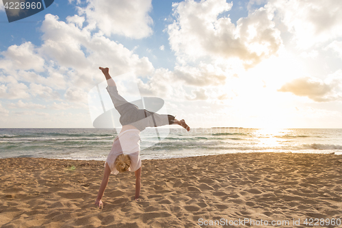 Image of Free Happy Woman Turning Cartwheel Enjoying Sunset on Sandy Beach.