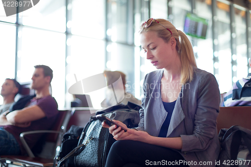 Image of Female traveler using cell phone while waiting on airport.