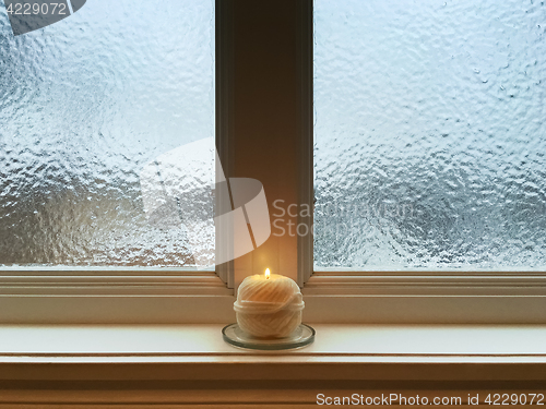 Image of Candle on windowsill of a frosted window