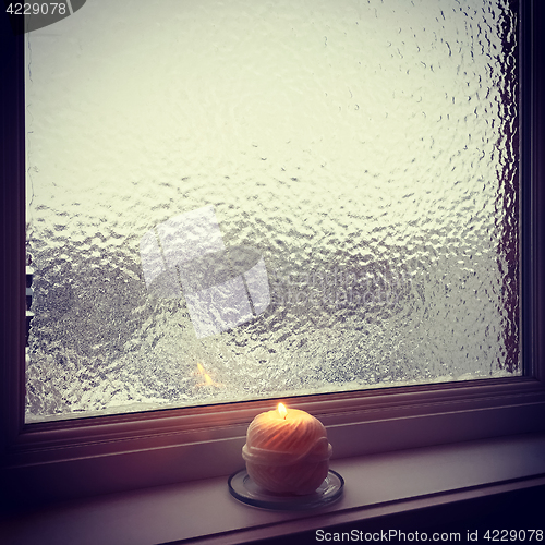 Image of Frosted winter window and burning candle