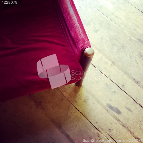 Image of Vintage red velvet armchair on wooden floor