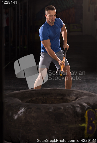 Image of man workout with hammer and tractor tire