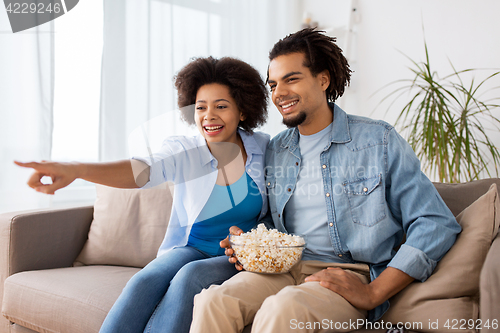 Image of smiling couple with popcorn watching tv at home