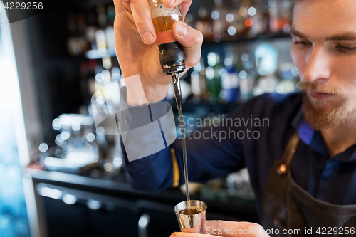 Image of barman with shaker preparing cocktail at bar