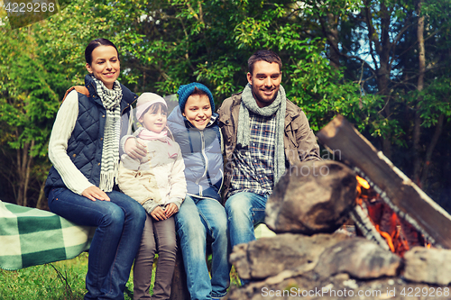 Image of happy family sitting on bench at camp fire