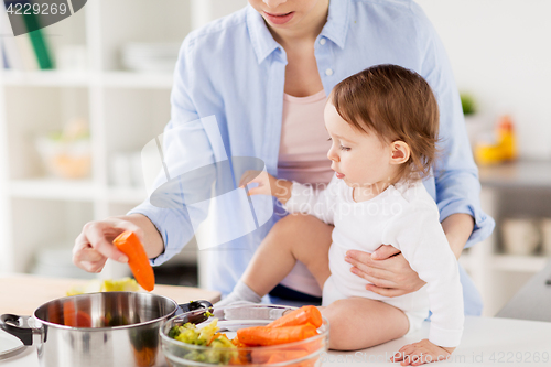 Image of happy mother and baby cooking vegetables at home