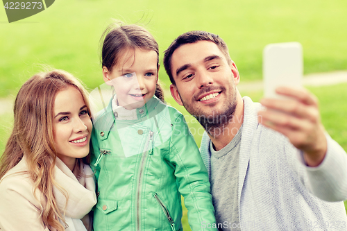 Image of happy family taking selfie by smartphone outdoors