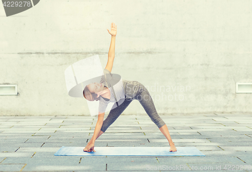 Image of woman making yoga triangle pose on mat