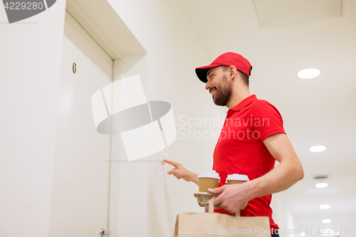 Image of delivery man with coffee and food ringing doorbell