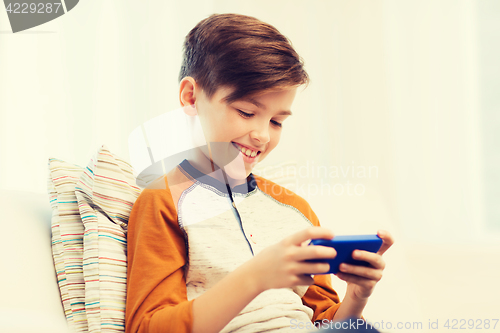 Image of boy with smartphone texting or playing at home