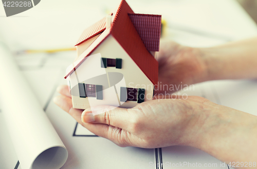 Image of close up of hands with house model above blueprint