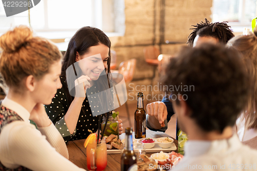 Image of happy friends eating and drinking at bar or cafe