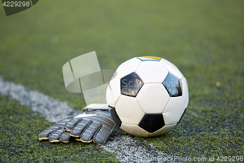 Image of soccer ball and goalkeeper gloves on field