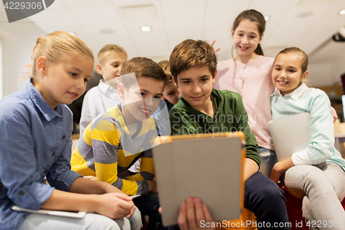 Image of group of happy children with tablet pc at school