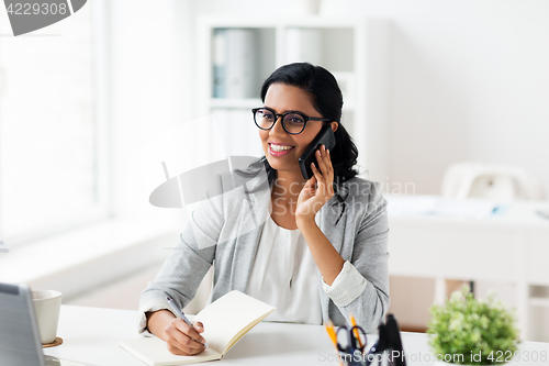 Image of businesswoman calling on smartphone at office