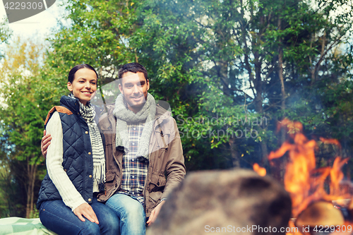 Image of happy couple sitting on bench near camp fire